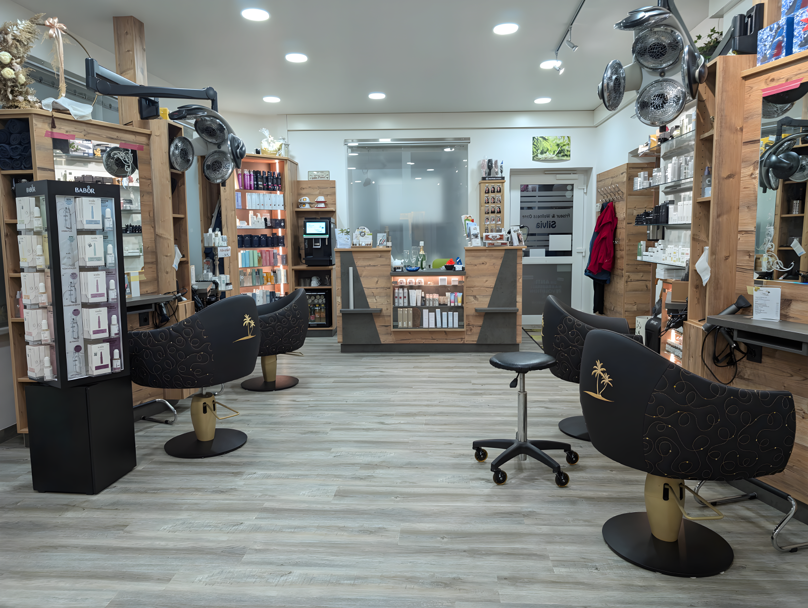 Innenansicht eines Kosmetik- und Friseursalons mit Behandlungsstühlen, Produktregalen und Empfangsbereich